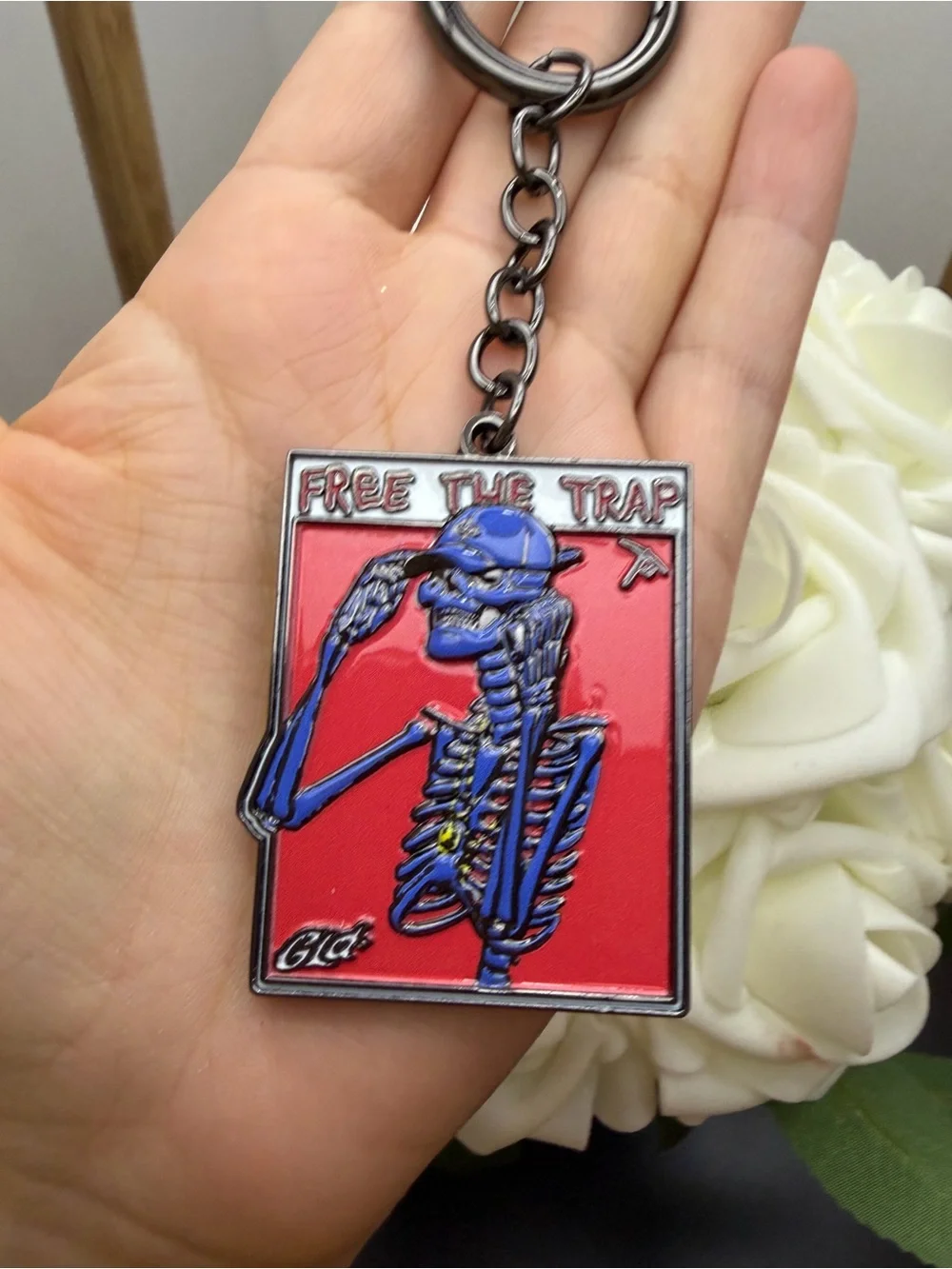 Blue Skeleton 'Free The Trap' Enamel Keychain on Red Background